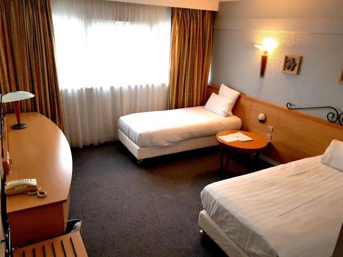 a hotel room with two beds and a window at Kyriad Prestige Mulhouse - Basel in Sausheim