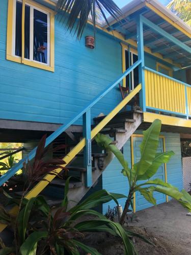 a blue house with blue stairs and a window at Colinda Cabanas in Caye Caulker