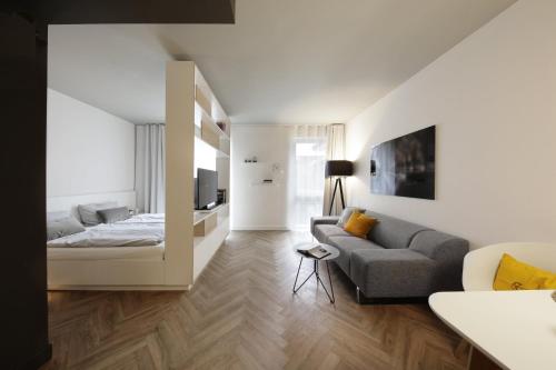 - un salon avec un lit et un canapé dans l'établissement SMARTments business München Parkstadt Schwabing, à Munich