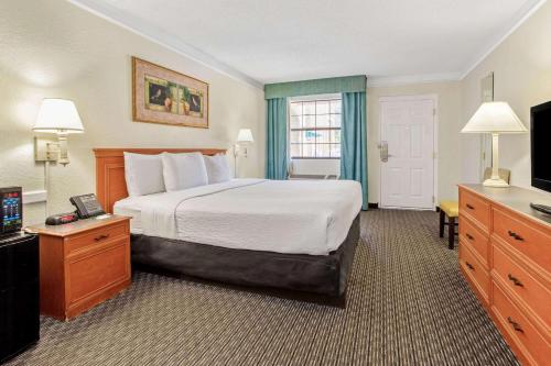 a hotel room with a bed and a television at La Quinta Inn by Wyndham Tampa Bay Pinellas Park Clearwater in Pinellas Park