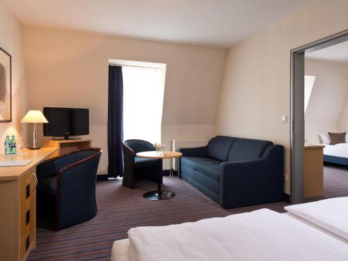 ein Hotelzimmer mit einem Bett, einem Sofa und einem TV in der Unterkunft ACHAT Hotel Dresden Elbufer in Dresden