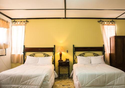 a bedroom with two beds with white sheets at Hotel Santa Elena in San Salvador