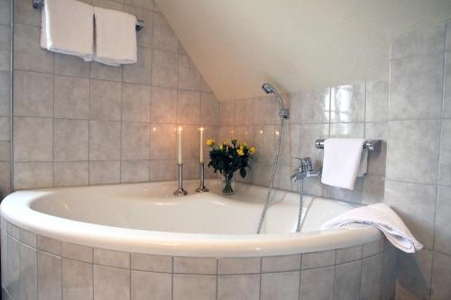 a bathroom with a tub with a vase of flowers in it at Hotel zur Altstadt in Freudenberg