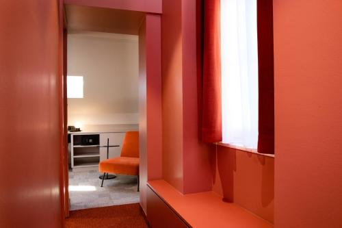a room with a red wall and a red chair at Hôtel Gutenberg in Strasbourg