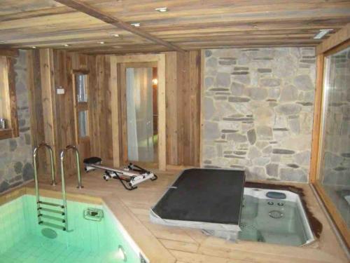 a bath tub in a room with a stone wall at Chalet Javen - 520m2 avec piscine chauffée et home cinéma in Megève