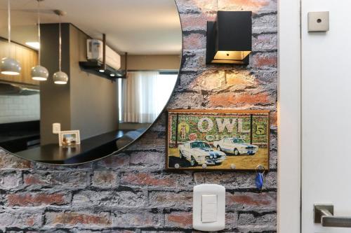 a mirror on a brick wall with a picture of a car at Studio Berlin - Central - 7th012 in Curitiba