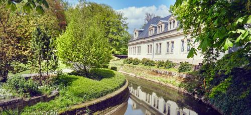 a building next to a river in front of a building at Mondorf Parc Hotel & Spa in Mondorf-les-Bains