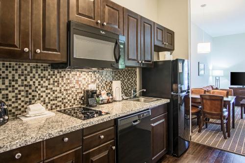 a kitchen with wooden cabinets and a black refrigerator at Sleep Inn & Suites West-Near Medical Center in Rochester