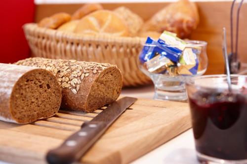 a loaf of bread on a cutting board with a glass of soda at Gästehaus Alpina in Bad Kohlgrub