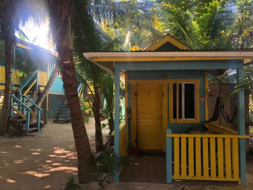 a small house with a yellow door and palm trees at Colinda Cabanas in Caye Caulker