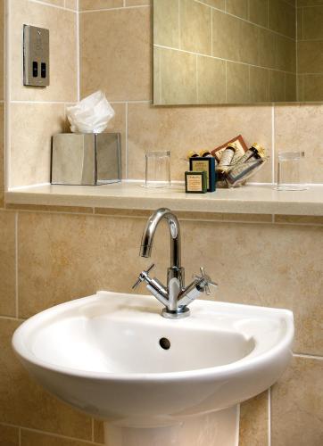 a bathroom with a sink and a mirror at Grovefield House Hotel in Slough