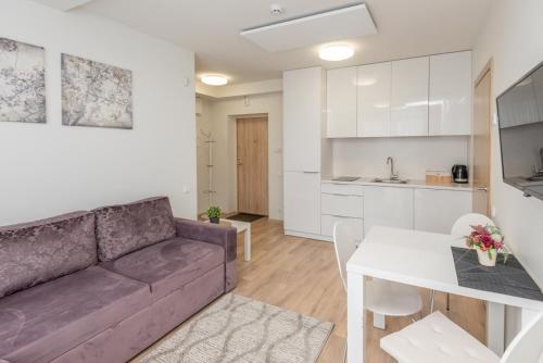ein Wohnzimmer und eine Küche mit einer Couch und einem Tisch in der Unterkunft Apartament Malūno in Palanga