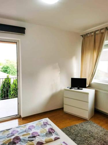 a white room with a television and a dresser and a window at Casa File de Poveste in Târgu Jiu