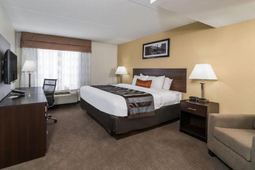 a hotel room with a large bed and a couch at Wingate by Wyndham Bowling Green in Bowling Green