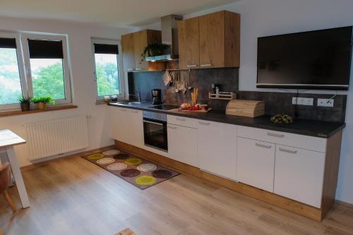a kitchen with white cabinets and a flat screen tv at Ferienwohnungen Hechenblaikner in Maurach
