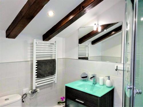 baño con lavabo verde y espejo en Casa Rural Madera y Sal, en Salinas de Añana