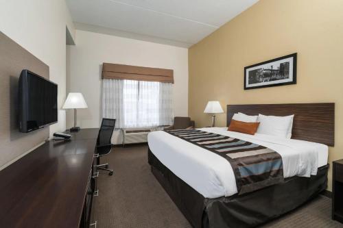 a hotel room with a large bed and a flat screen tv at Wingate by Wyndham Bowling Green in Bowling Green