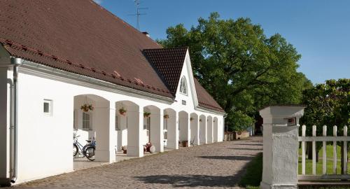 a white building with a brown roof and a fence at Sagadi Manor Hotel in Sagadi