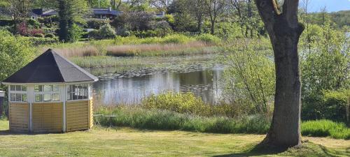 a gazebo in the grass next to a lake at Hotel apartment with a lake view - 2 room apartment in Kruså