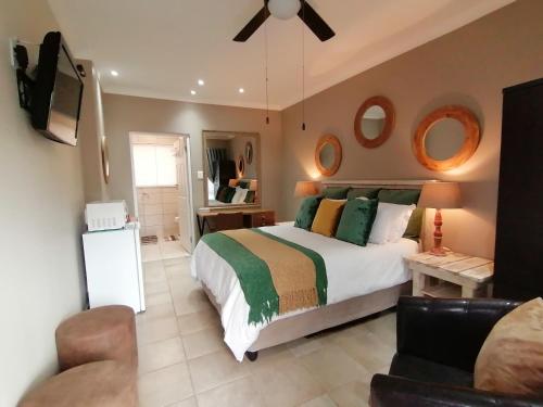 una camera da letto con un letto, una TV e un divano di Roxy's Rest Guest House a Vanderbijlpark