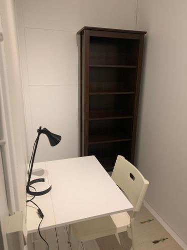 a white desk with a lamp and a book shelf at Villa Västanede in Västanede
