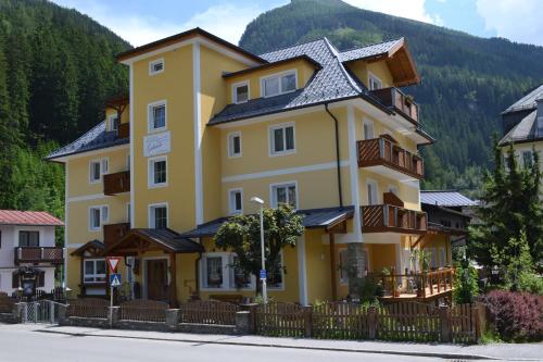 a yellow building with a fence in front of a mountain at Pension Appartements Gabriele in Bad Gastein