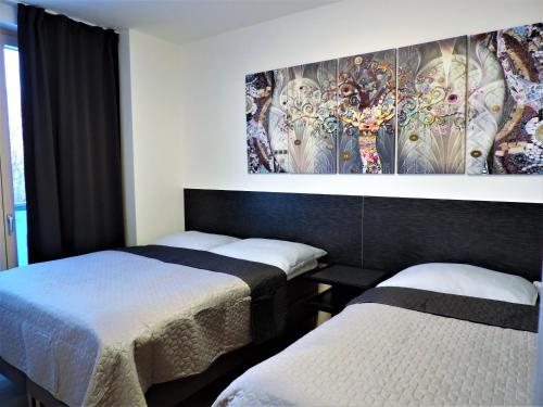 two beds in a room with a painting on the wall at Apartman Bery, Vysoké Tatry in Starý Smokovec