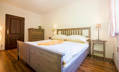 um quarto com uma cama grande com lençóis brancos e almofadas em Apartmány Hrabovská dolina em Ruzomberok