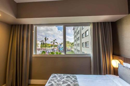 a bedroom with a window with a view of a city at Tauá Hotel & Convention Atibaia in Atibaia