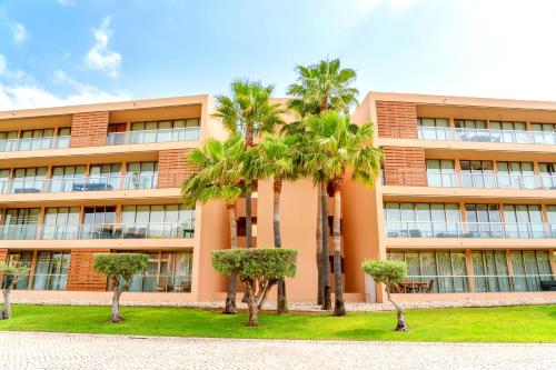 a building with palm trees in front of it at Regenbogen Properties - Salgados Vila das Lagoas in Albufeira