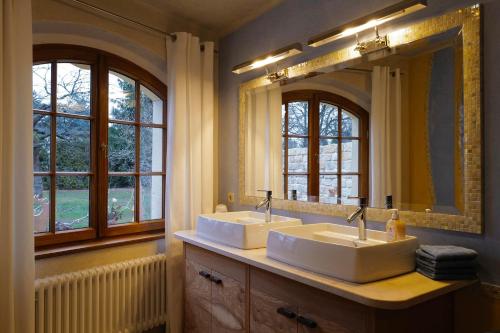 two sinks in a bathroom with two mirrors at Ferienhaus Zur Ausspanne in Dresden