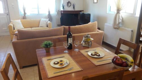 una sala de estar con una mesa con comida y una botella de vino en Ideal Family House en Néa Péramos