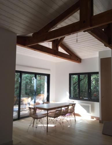 une salle à manger avec une table, des chaises et des fenêtres dans l'établissement Villa Framboise, à Lège-Cap-Ferret