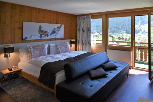 a bedroom with a bed and a couch and a window at Hotel Cabana in Grindelwald