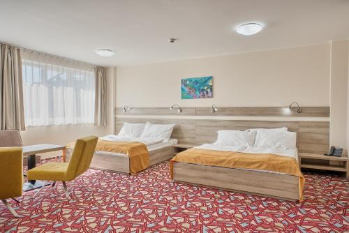 a hotel room with two beds and a chair at Hotel Arena in Chomutov