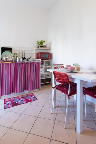 a kitchen with a white table and red chairs at Marialuisa's Home - Le Rive Del Lago in Desenzano del Garda