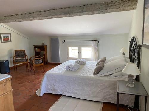 a bedroom with a large white bed with towels on it at Le Mas de la Martelière in Le Thor