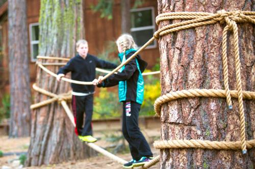 two boys playing on a rope bridge around a tree at Evergreen Lodge at Yosemite in Groveland