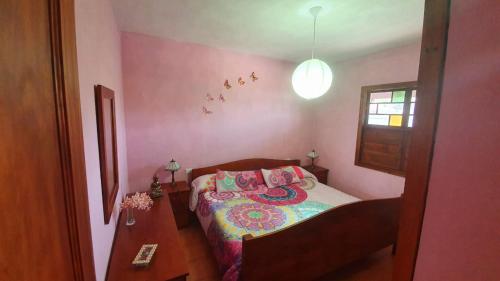 a small bedroom with a bed with pink walls at Casa Marco in Puntagorda
