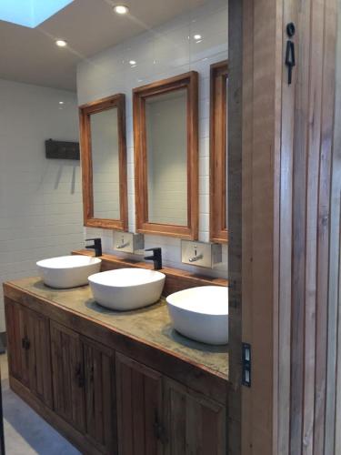 three sinks in a bathroom with three mirrors at Hostal Boutique Factoria Patagonia in Puerto Natales