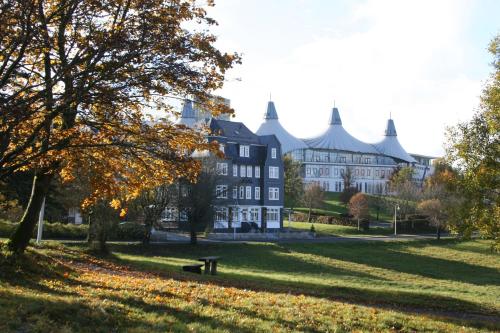 a large building in a park with a bench in front at Hotel & Café Daheim in Masserberg