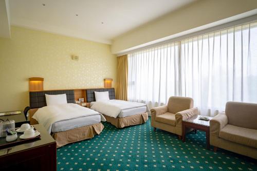 Habitación de hotel con 2 camas y 2 sillas en 柳營尖山埤 Liuying Jianshanpi Resort, en Liuying