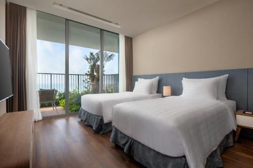 two beds in a hotel room with a balcony at Flamingo Resort Cat Ba in Cat Ba