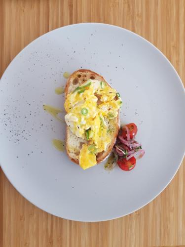 a white plate with a breakfast sandwich on a table at Whangaparaoa Lodge in Whangaparaoa