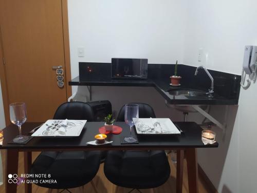 a table with two plates of food and wine glasses at Terraço Harmony Flats GRU in Guarulhos