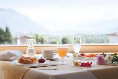 einen Tisch mit Speisen und Getränken auf einem Tisch mit Fenster in der Unterkunft Hotel Tobler in Ascona