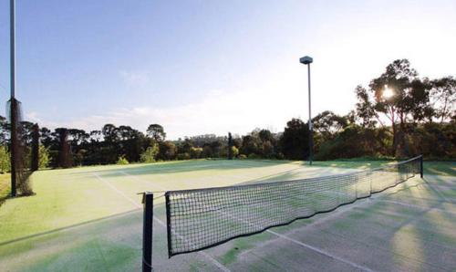 a tennis court with a tennis net on it at Merricks North Retreat in Merricks North