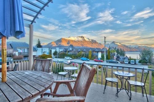 a deck with a table and chairs and a view of a mountain at Melbourne Lodge in Queenstown