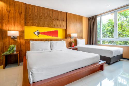 a bedroom with two beds and a yellow and red wall at MeStyle Place Hotel in Bangkok