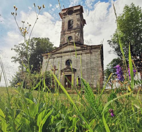 an old building with a clock tower in a field at Apartmán v podkroví in Říčky